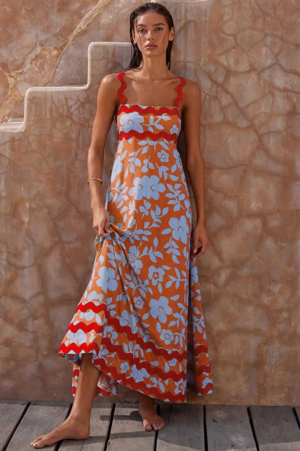 Vestido maxi naranja con un patrón floral blanco y un ribete rojo ondulado en las tiras, el escote y el bajo, diseñado como un vestido maxi de playa en corte A con dobladillo ondulado floral.
