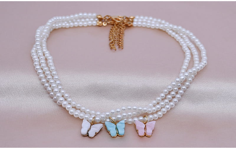 Elegant pearl butterfly charm choker necklace featuring a delicate triple-strand pearl design with three pastel enamel butterfly charms in white light blue and pink.