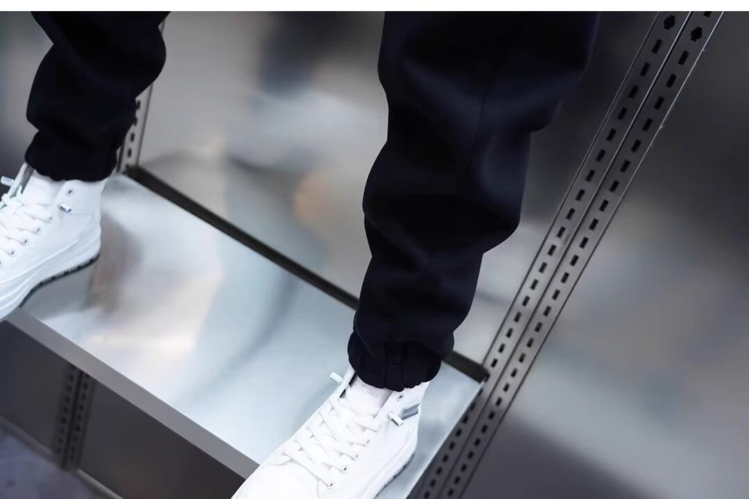 mens casual solid color sweatpants paired with white high-top sneakers featuring black laces and a sleek modern design.