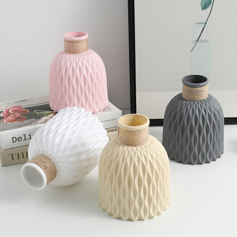Set of four modern textured ceramic vases in pastel pink white beige and gray with natural twine-wrapped necks and wavy texture.