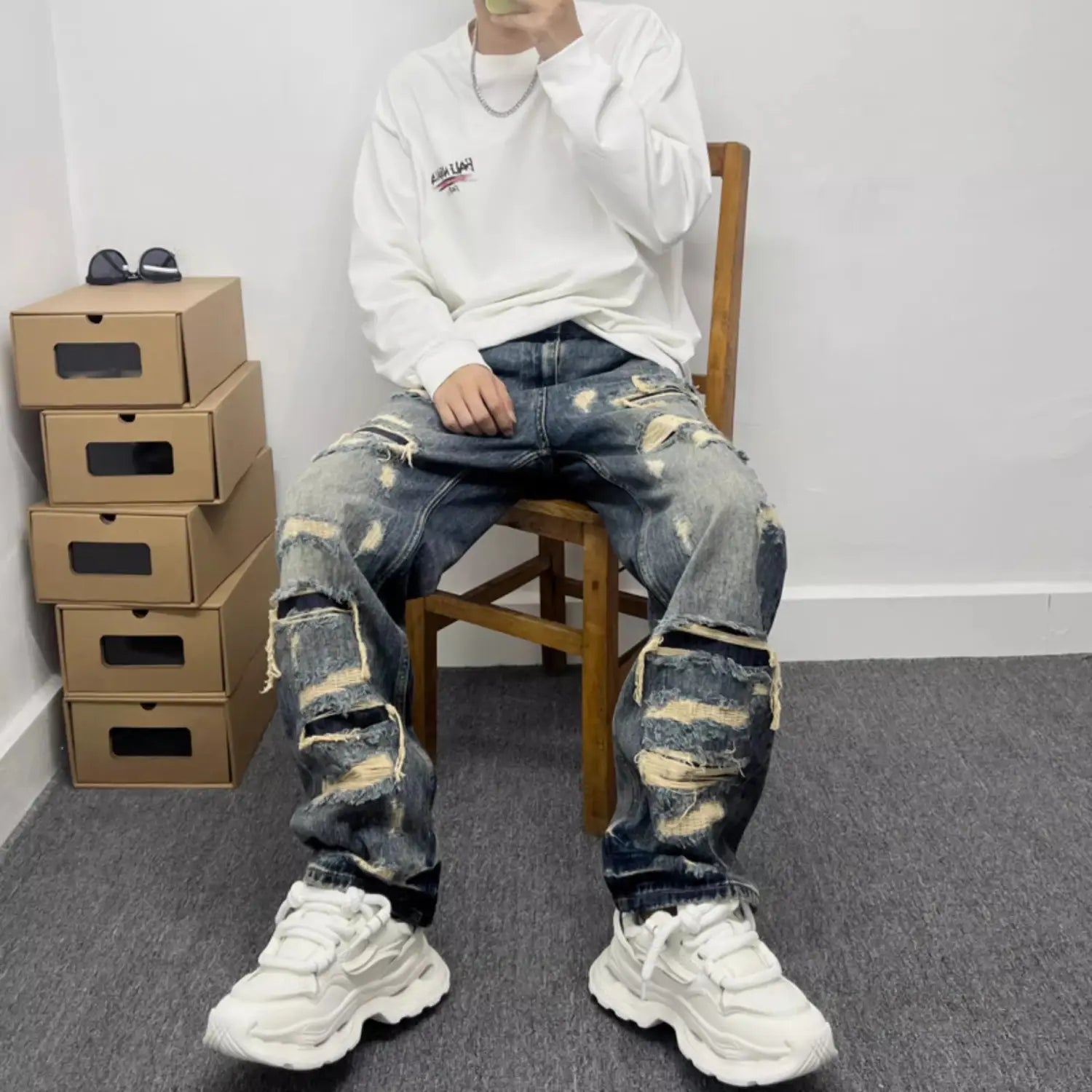 Men’s light blue denim jeans featuring distressed design with multiple ripped and frayed patches.