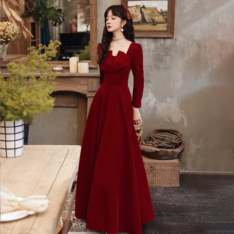 a rich burgundy velvet long sleeve a-line gown featuring a square neckline and elegant full sleeves