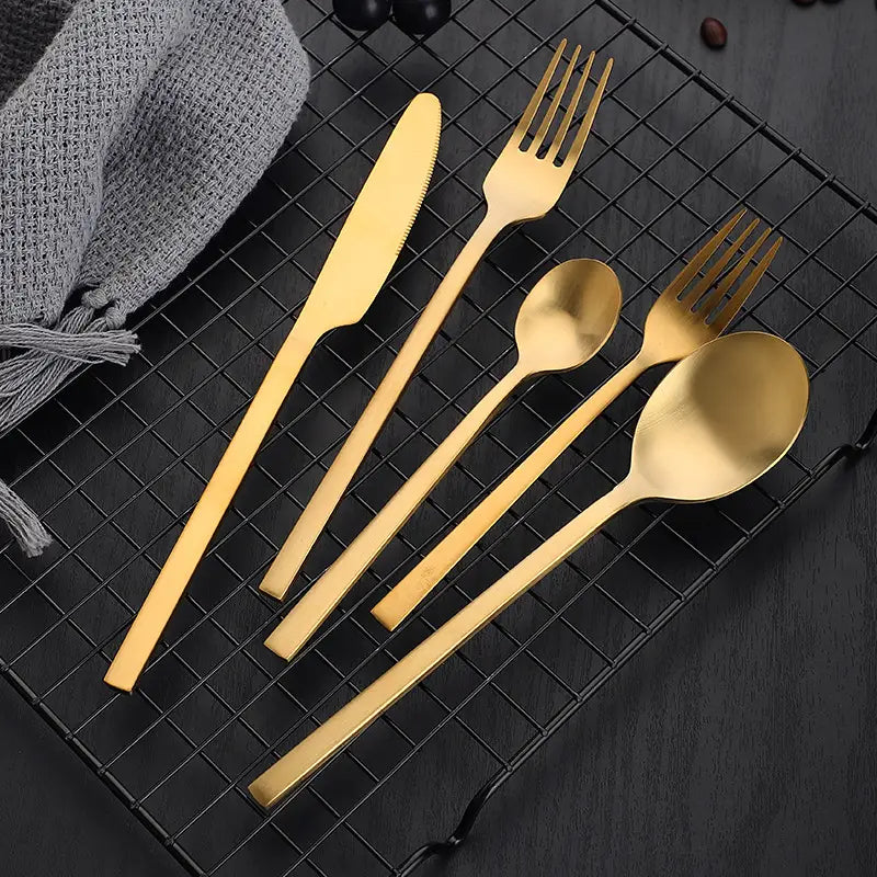 Ensemble de couverts en acier inoxydable doré, au design moderne et épuré, présentant des surfaces mates et finies dorées polies.