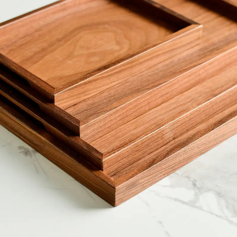 Stacked acacia wood rectangular serving trays with a rich warm brown finish and visible natural wood grain hand polished for enhanced durability.