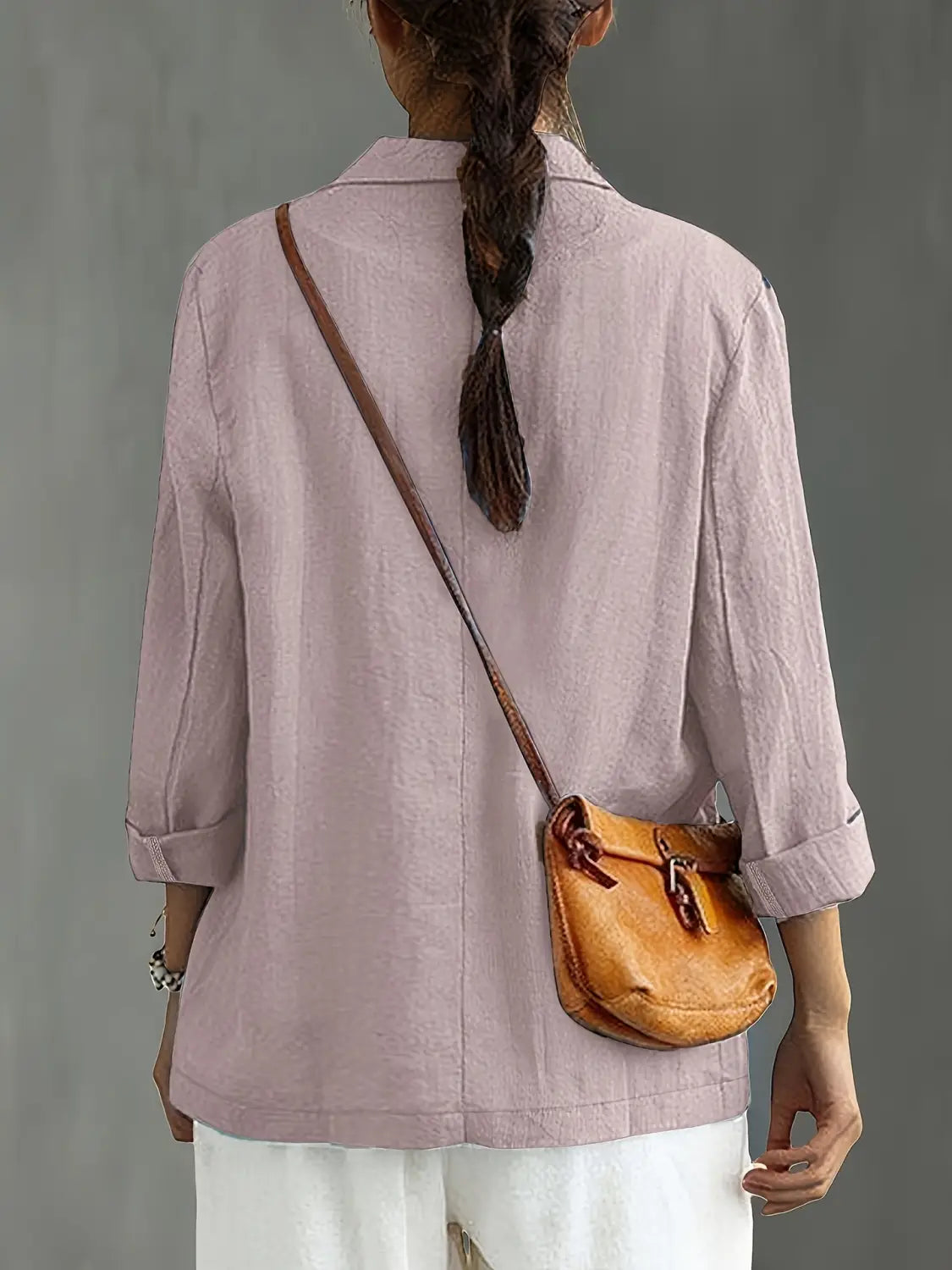 Un bolso cruzado de cuero color camel con cierre de solapa y correas marrones, complementa un blazer de lino para mujer, casual y de trabajo.