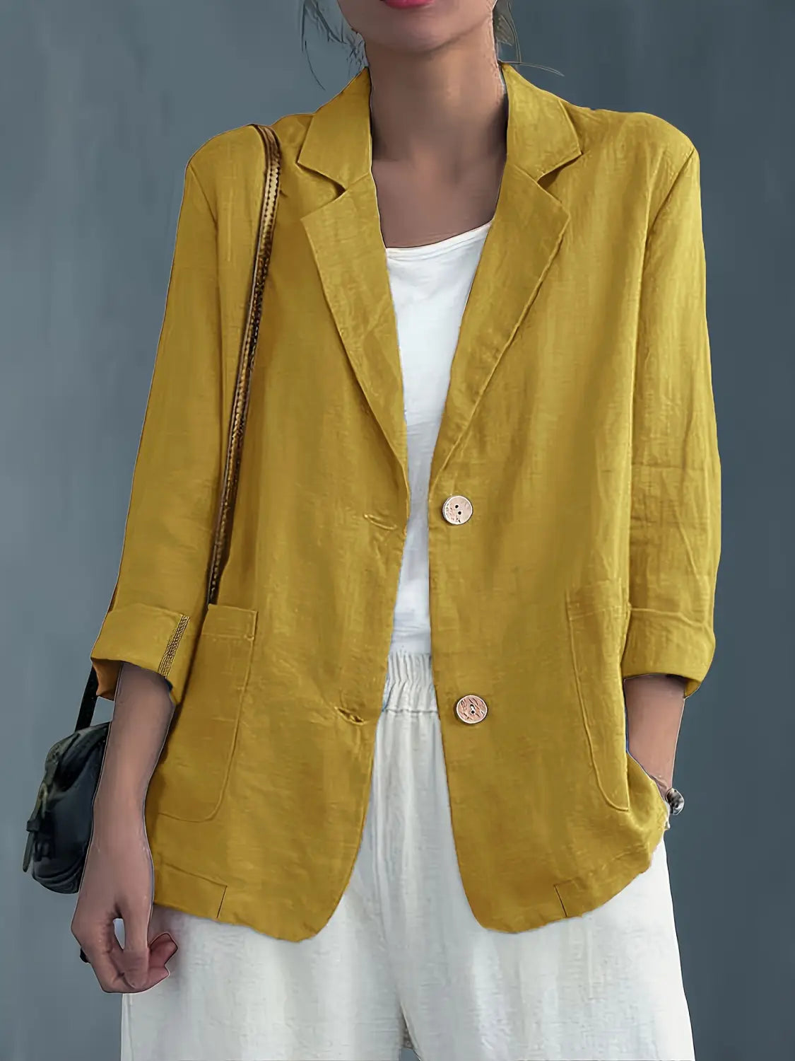 Blazer de lino color amarillo con dos botones de madera y mangas remangadas, diseñado como chaqueta de trabajo casual para mujer.