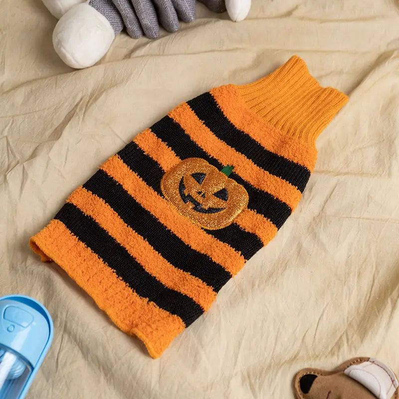 Orange and black striped knitted Halloween dog sweater featuring a glittery pumpkin patch design for pet costume use.