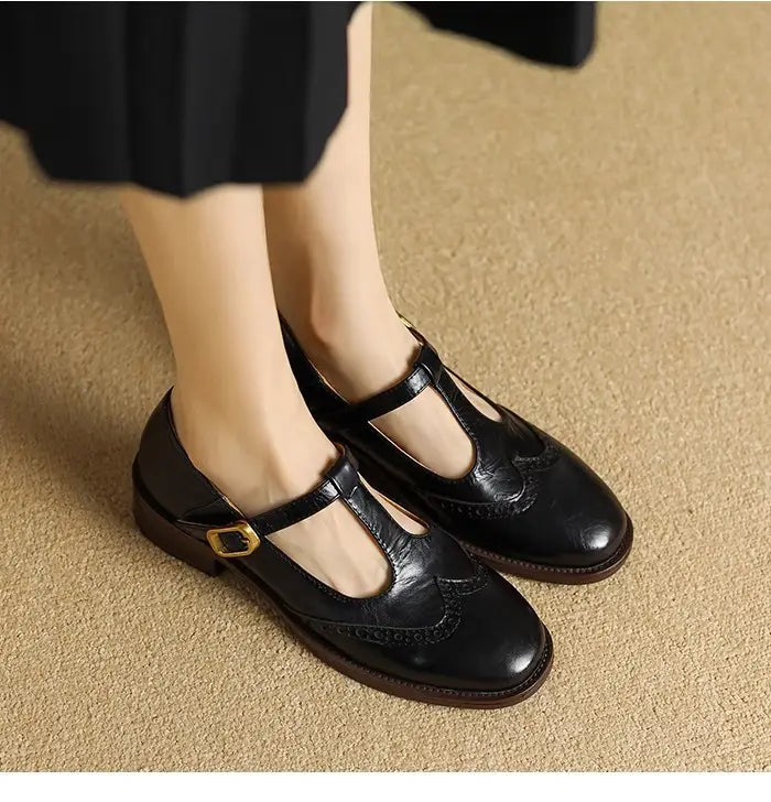 Schwarze Leder-Mary-Jane-Pumps mit klobigem Absatz mit goldfarbenem Schnallenverschluss und Brogue-Verzierung.