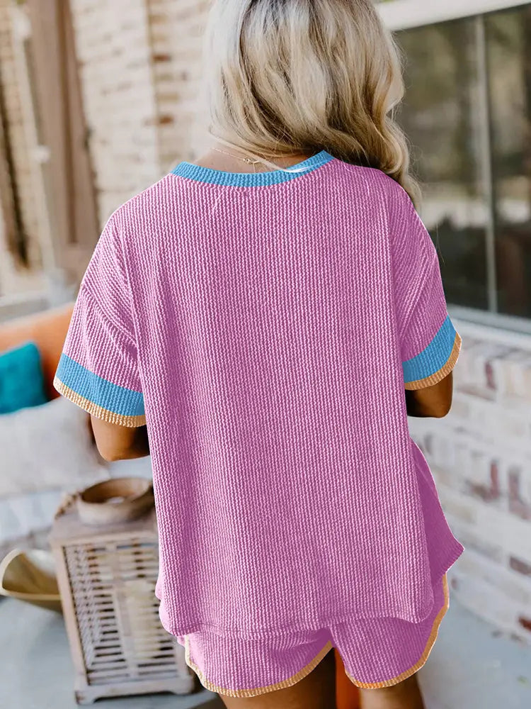 pink ribbed knit two-piece lounge set with blue and yellow contrast trim highlighting the edges and cuffs