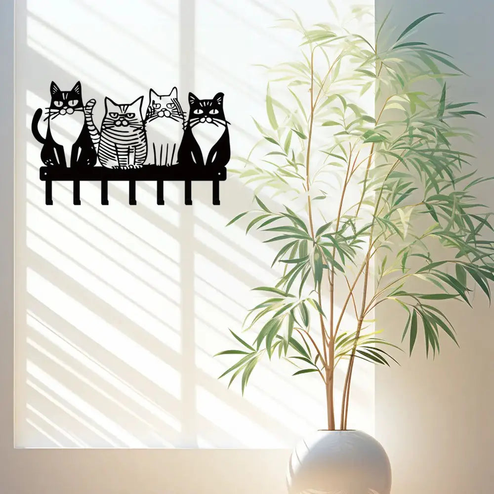 Black metal wall key rack with four stylized cats sitting on a bench featuring four hooks for home decor.