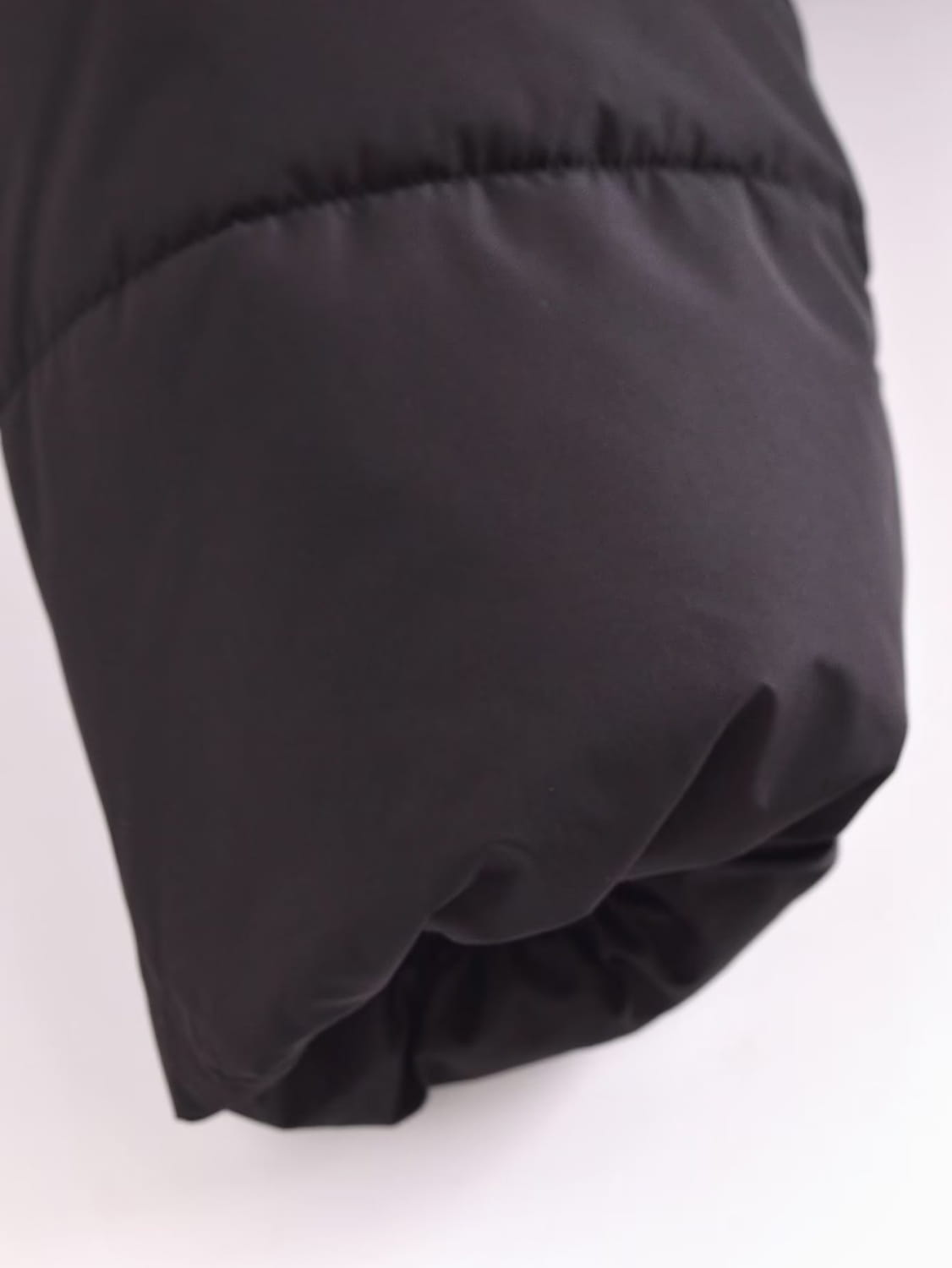 Black quilted hooded puffer coat sleeve in black with quilted stitching and a slightly gathered cuff.