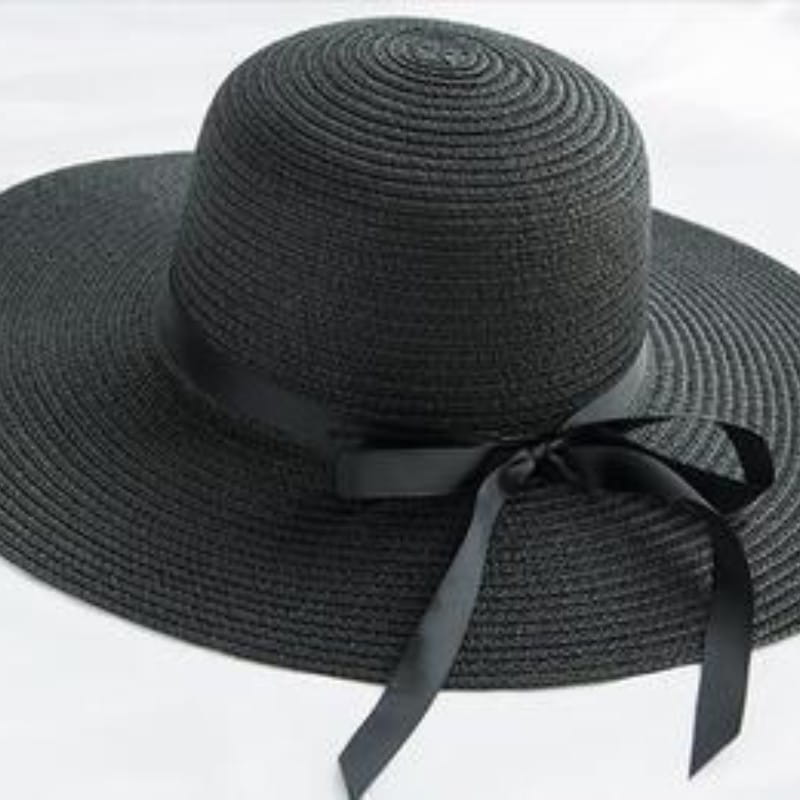 Black woven straw wide brim sun hat with a matching black satin ribbon bow around the crown for sun protection.