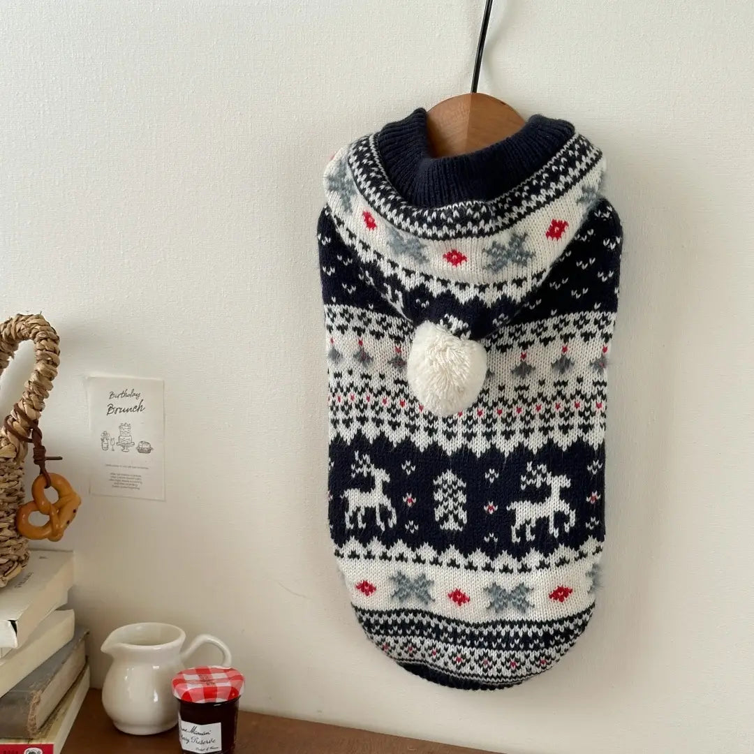 Pull en tricot nordique pour chien bleu marine et blanc, avec des flocons de neige de rennes, des accents rouges et un pompon duveteux sur la capuche, conçu pour des vêtements d’hiver chauds pour animaux de compagnie.