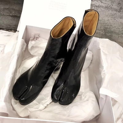 Black patent leather split toe tabi high heel ankle boots with a glossy finish and tan lining.