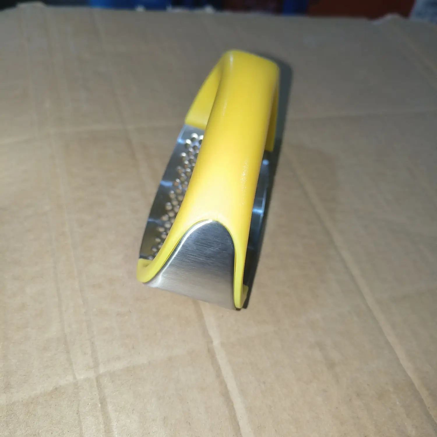 Presse-ail à poignée jaune, outil de hachage manuel ergonomique avec surface de râpage en acier inoxydable.