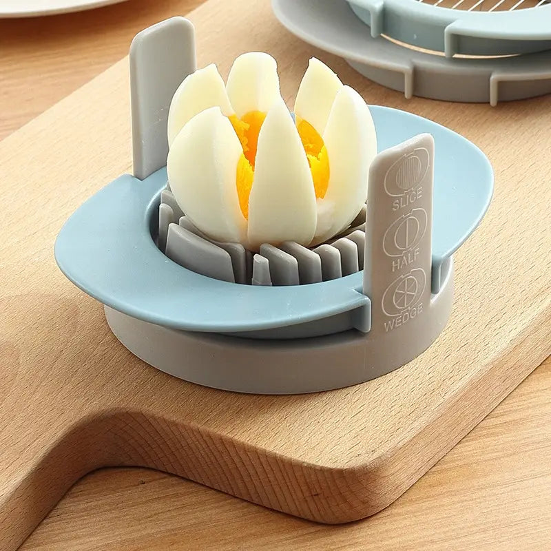 Hellblaue und graue Kunststoff-3-in-1-Eierschneidemaschine und manuelles Zwiebelzubehör mit verstellbaren Einstellungen zum Schneiden, Halbieren oder Keilen von hartgekochten Eiern.