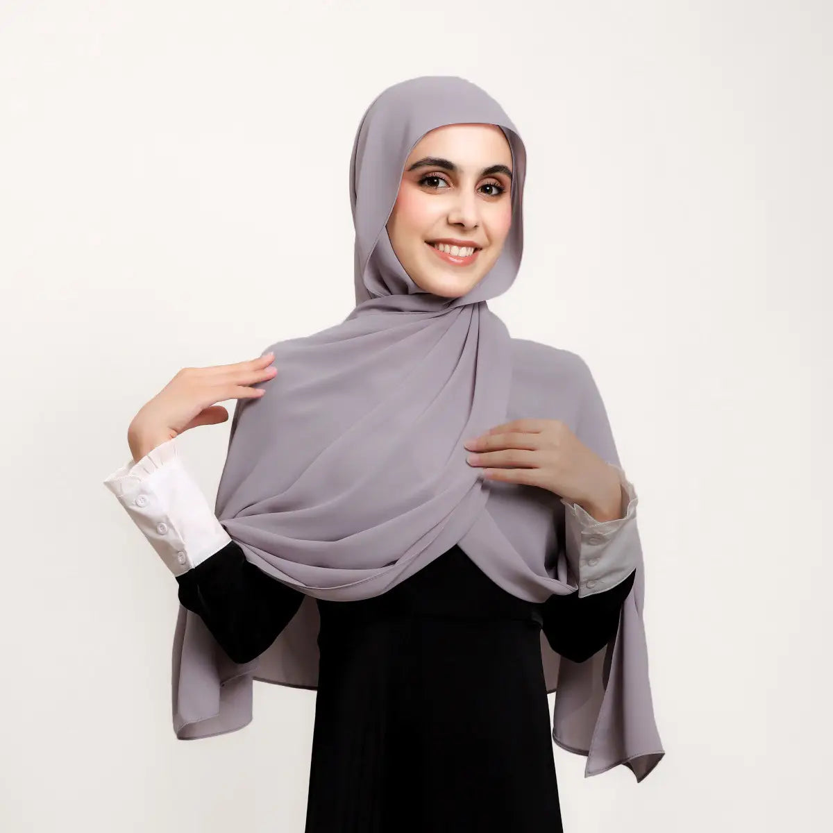 Un hijab en mousseline magnétique couleur unie kaki, réalisé dans un tissu léger, se drape avec élégance sur la tête et les épaules de la personne qui le porte.