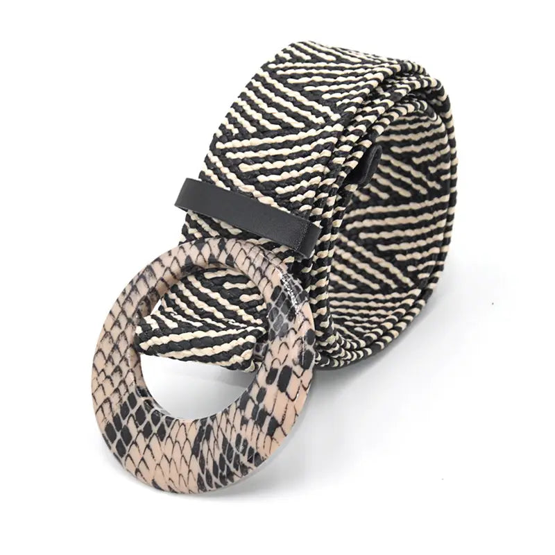 A woven elastic belt with a black and cream zigzag patterned fabric strap and a circular buckle featuring a beige snakeskin texture.
