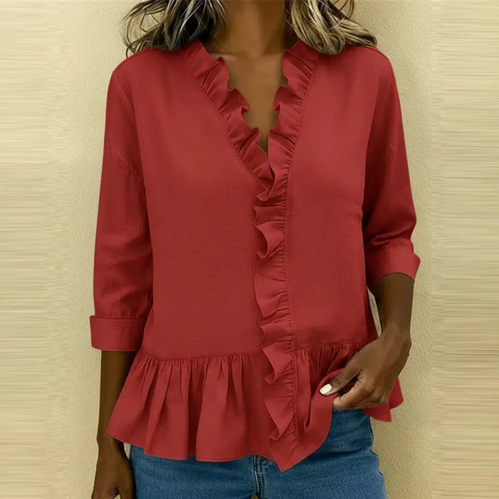 A soft coral-colored solid color ruffle hem peplum t-shirt featuring a v-neckline, ruffled detailing along the front placket, and three-quarter length sleeves rolled up at the cuffs.