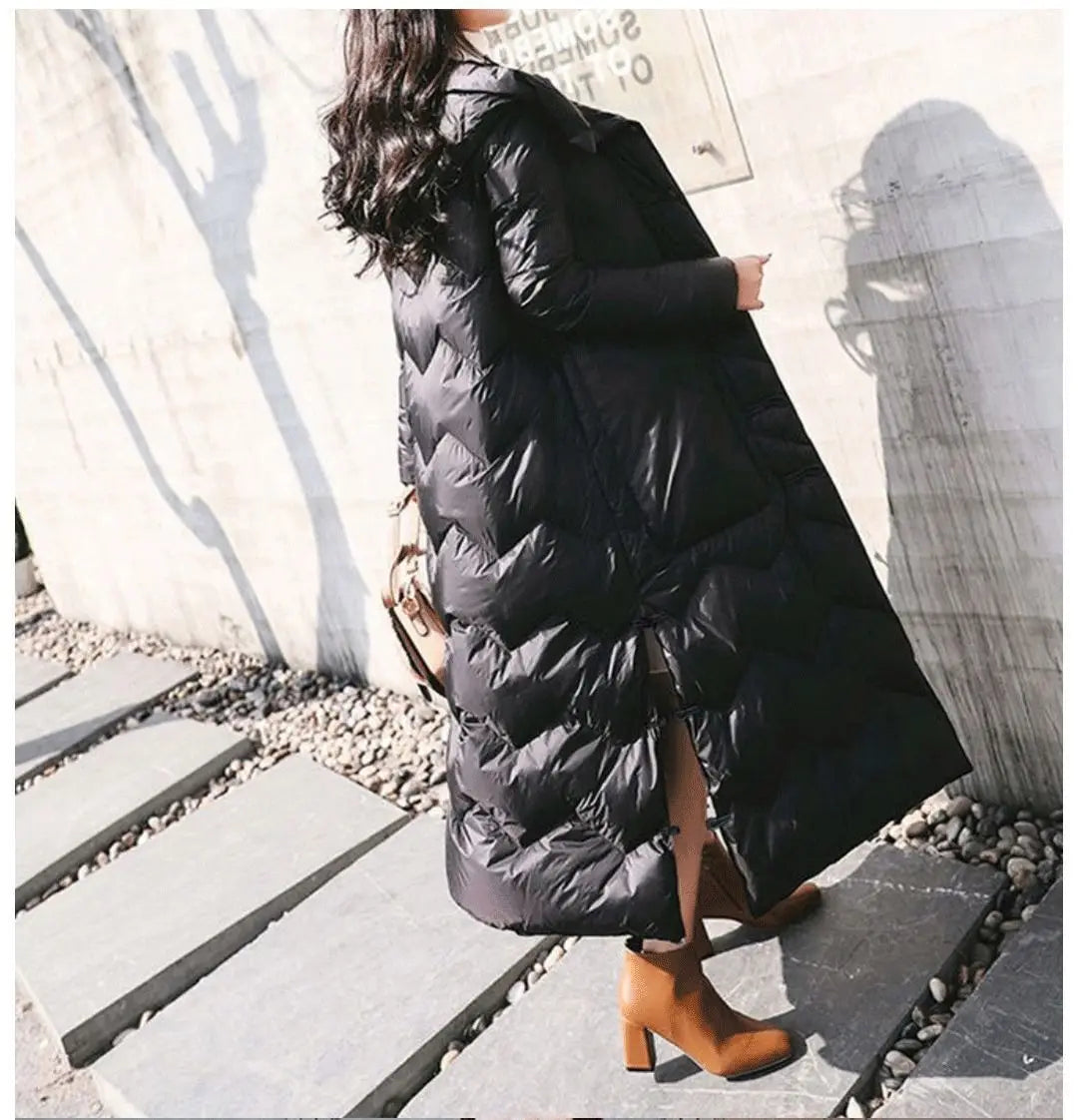 Manteau matelassé noir à boutons grenouille chinois, silhouette longue et fluide, avec fente latérale.