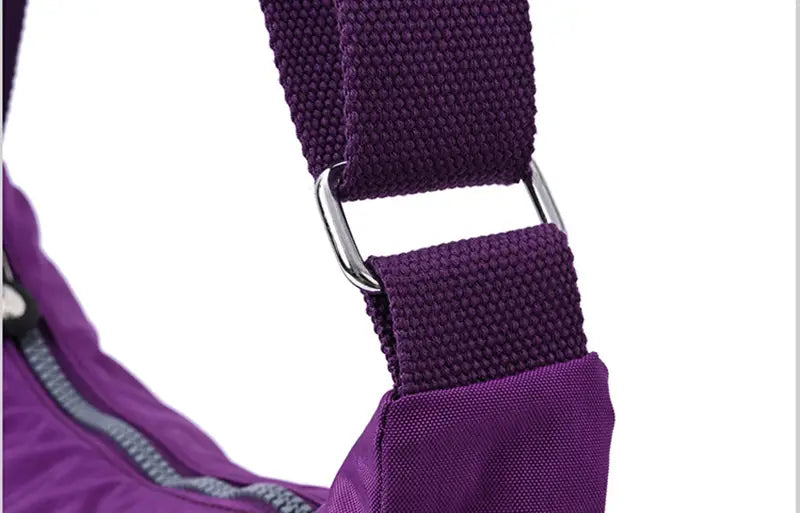 Purple woven fabric strap with silver metal buckle on waterproof multi pocket nylon crossbody shoulder bag