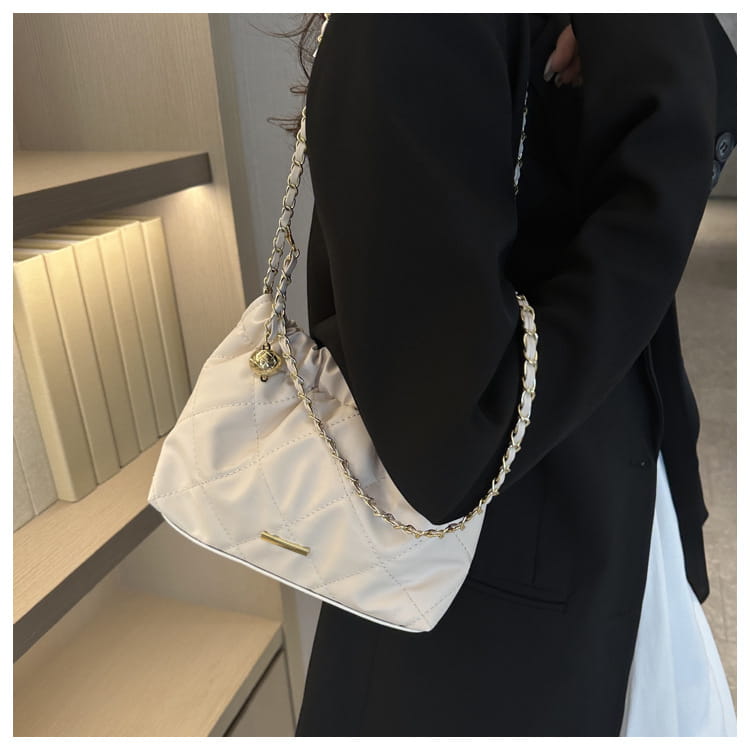 White quilted faux leather crossbody bag with gold-tone chain strap and small decorative clasp.