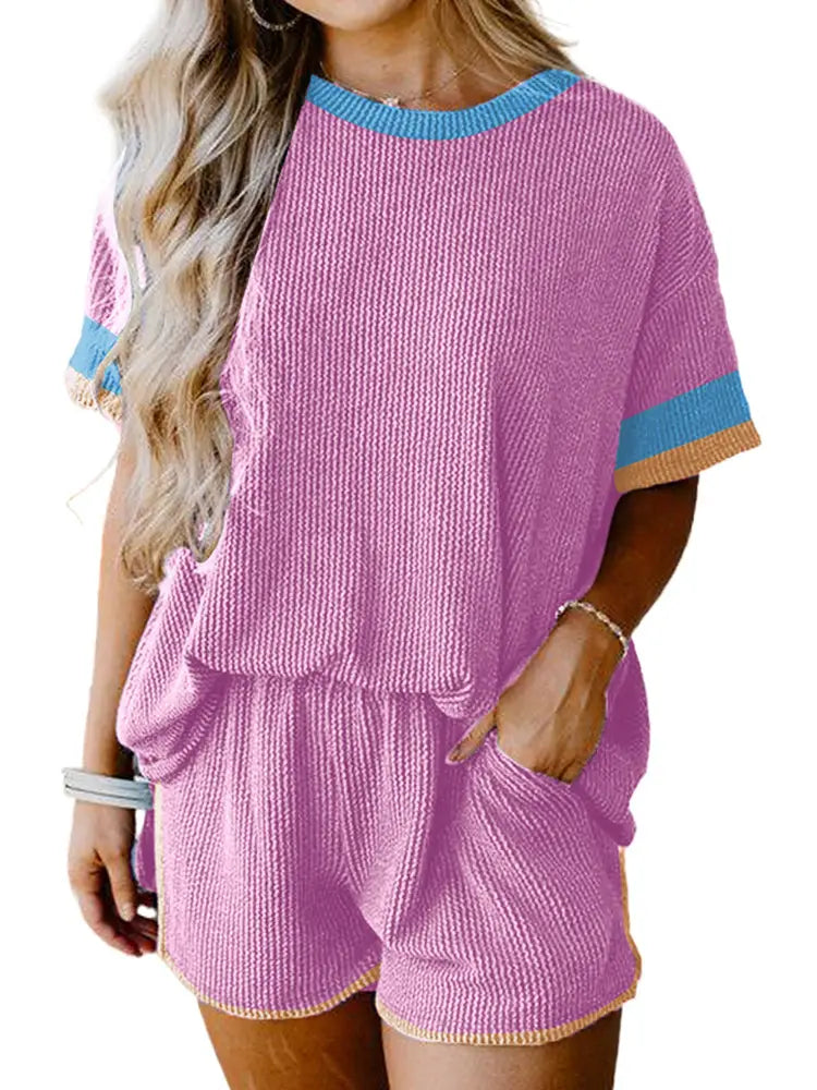 Pink ribbed knit two-piece lounge set with blue and beige contrast trim on the neckline sleeves and hem.