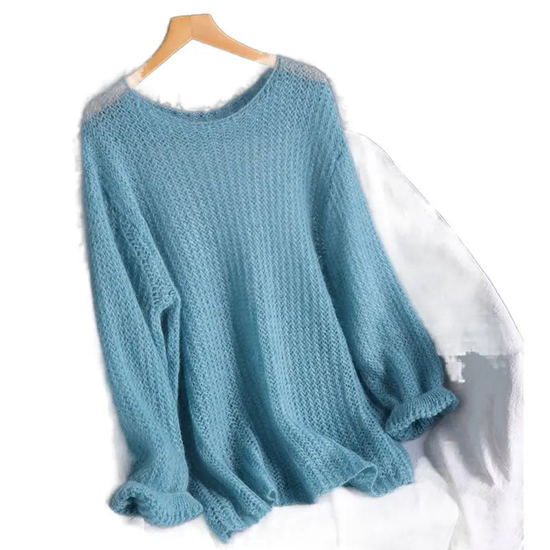 Ein weiches leuchtend hellblaues Pulloveroberteil in offener Strickoptik, als Blusenstil gestricktes Oberteil, mit lockerer Passform und gerippten Bündchen, hängt auf einem Holzkleiderbügel.