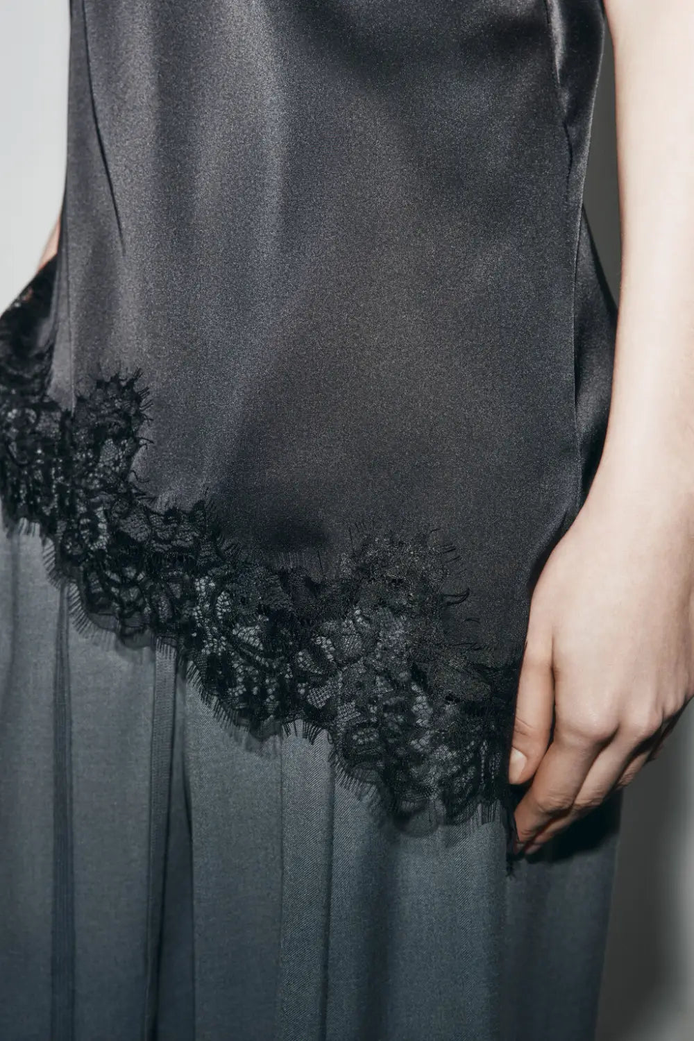Ein elegantes schwarzes Slip-Kleid aus Satin mit zartem Spitzenbesatz am Saum, als Alternative zu einem braunen Satin-Camisole-Top mit Spitzenbesatz dargestellt.