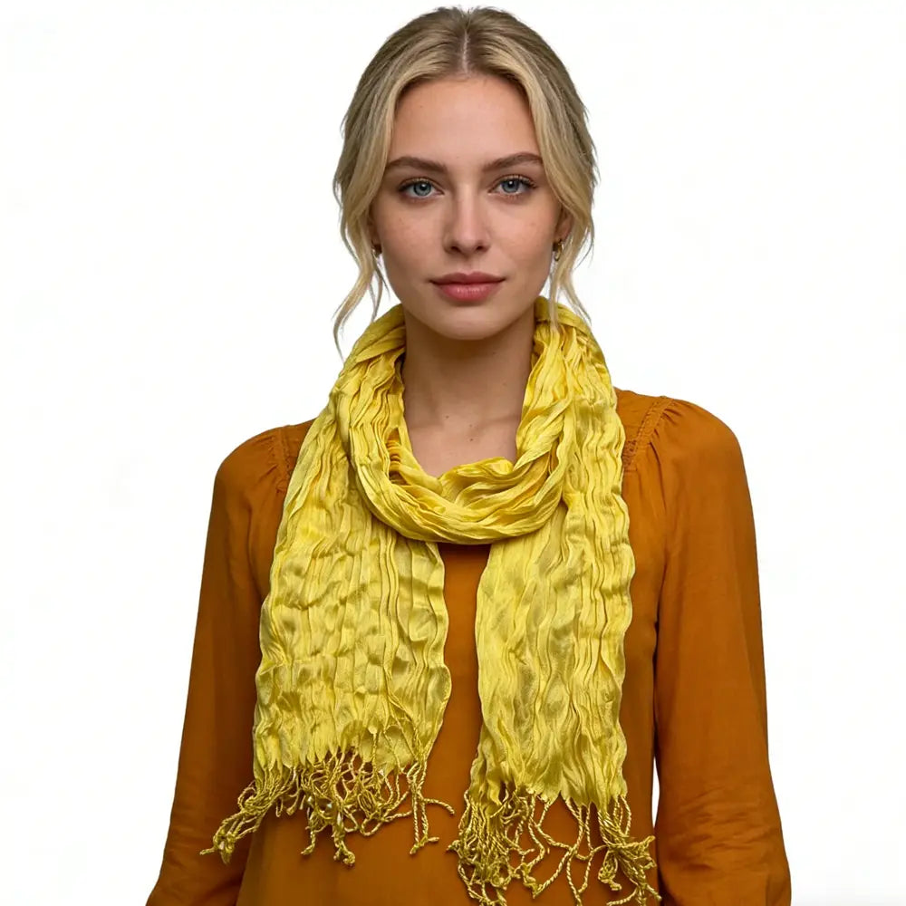 Un foulard froissé jaune vif, fabriqué dans une soie d’été texturée, avec des bords à franges, porté autour du cou.