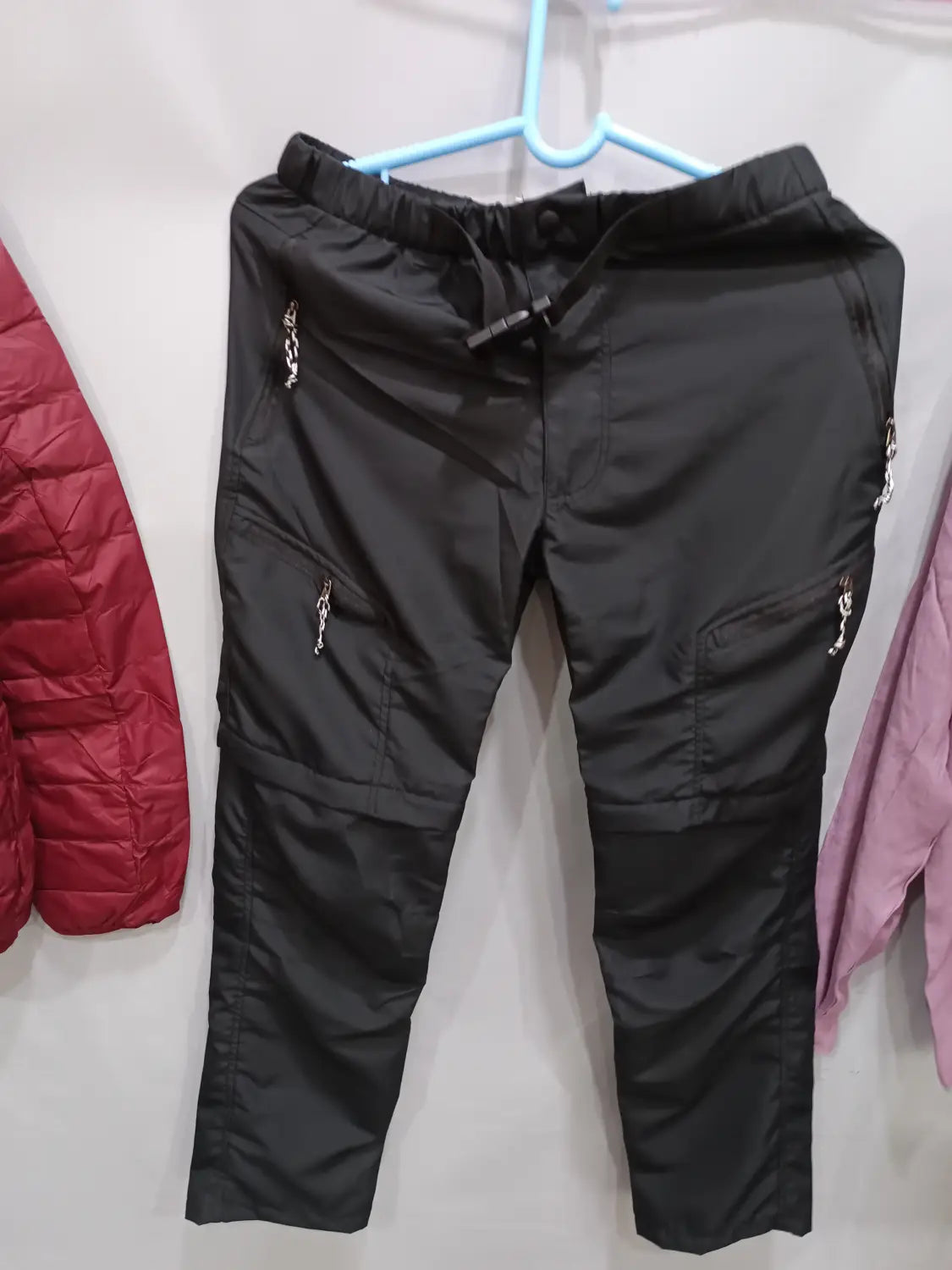 Black convertible tactical hiking pants featuring reflective chain detailing on the side pockets.