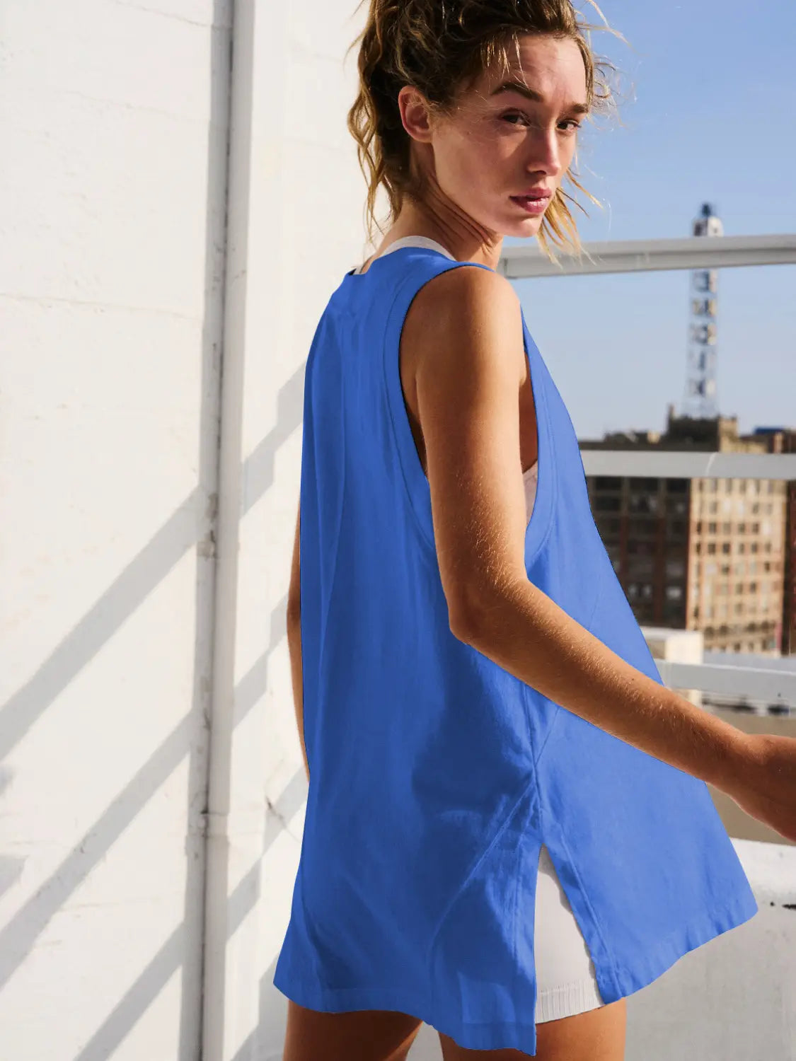 A vibrant blue relaxed v neck sleeveless cotton wrap vest top shown from the back with an open design and lightweight fabric.