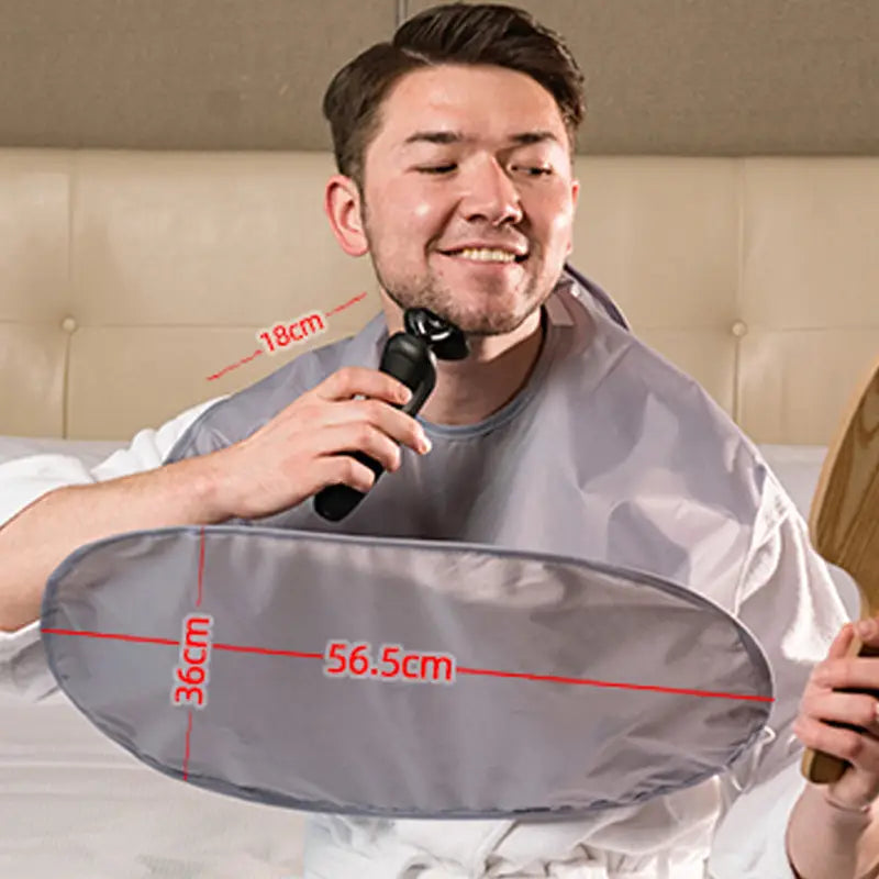 Graues, wasserdichtes Pflege-Cape mit Abmessungen von 56,5 cm mal 36 cm und einer 18 cm breiten Halsöffnung, ausgelegt für Rasur- und Haarentfernungssitzungen im faltbaren, wasserdichten Friseur-Cape-Schürzen.