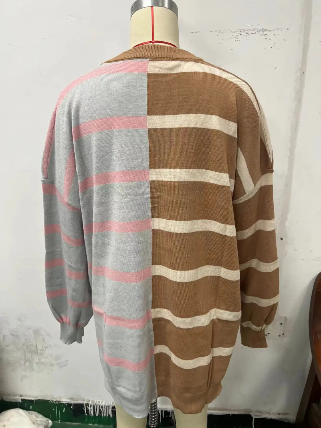 Women’s oversized split color striped knit sweater featuring a cozy oversized cardigan with soft gray and pink stripes on one half and warm brown and cream stripes on the other half.