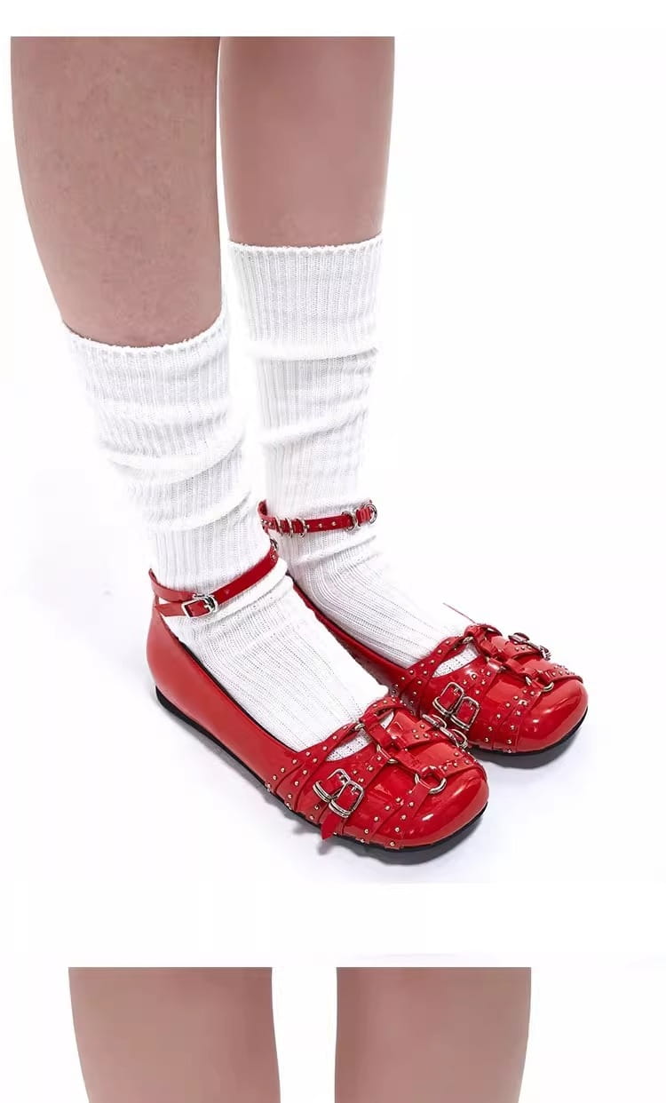 zapatos tipo salón retro de cuero con correas de hebilla con tachuelas en charol rojo, con hebillas de tono dorado y lazos decorativos.