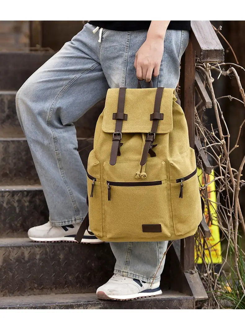 Men’s canvas travel backpack in mustard yellow with brown leather straps and accents featuring large 20-35l capacity.