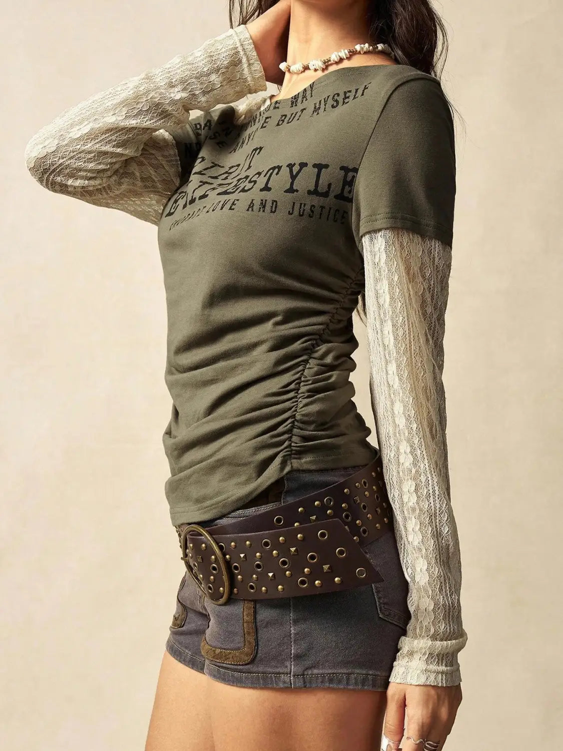 Olive green lace layer off shoulder knitted top with sheer lace long sleeves and a ruched bodice featuring black printed text.