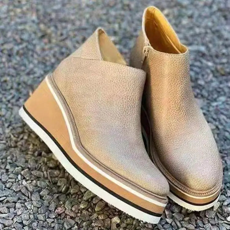 Botines de mujer de cuero color beige con plataforma gruesa en cuña y suela a rayas blanca y negra.