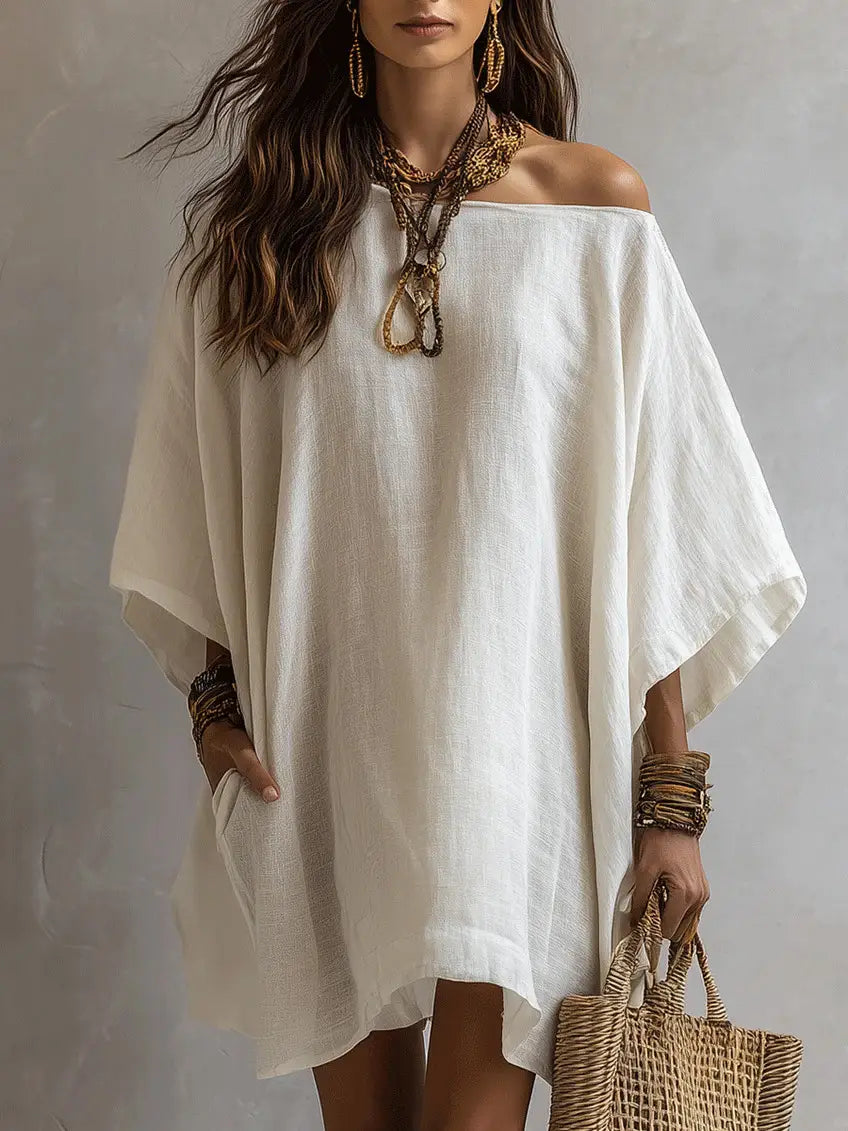 Robe en lin blanche à épaules dénudées et manches kimono, présentant un design fluide à épaules dénudées, une coupe ample et décontractée, ainsi qu’une texture subtile