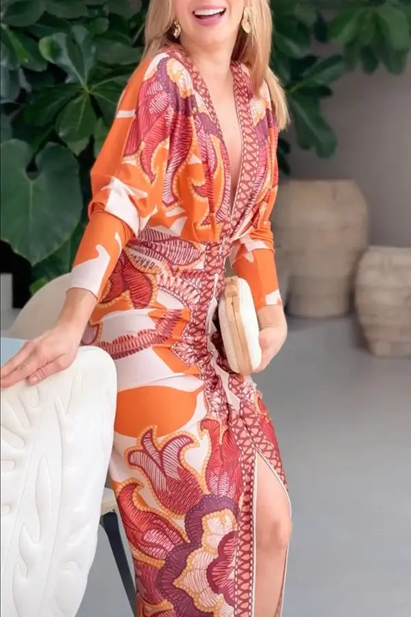 A printed v-neck geometric wrap midi dress in vibrant orange red and white with a deep v-neckline and side slit.
