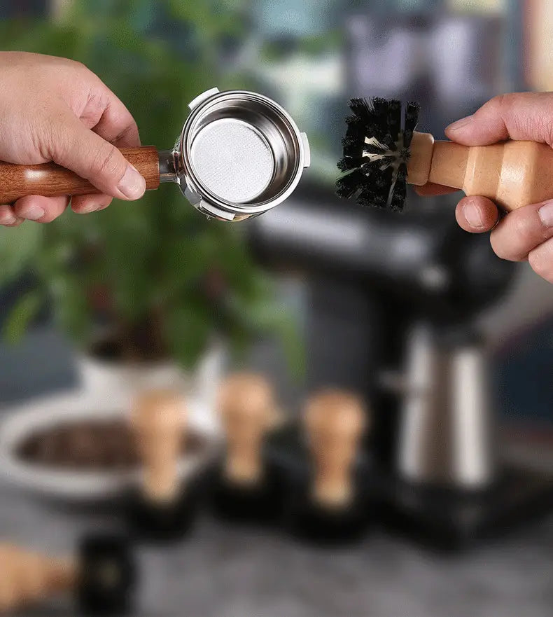 A wooden-handled espresso portafilter with a stainless steel filter basket being cleaned by a matching wooden-handled brush from the coffee machine cleaning brush set 4 piece wood handle.