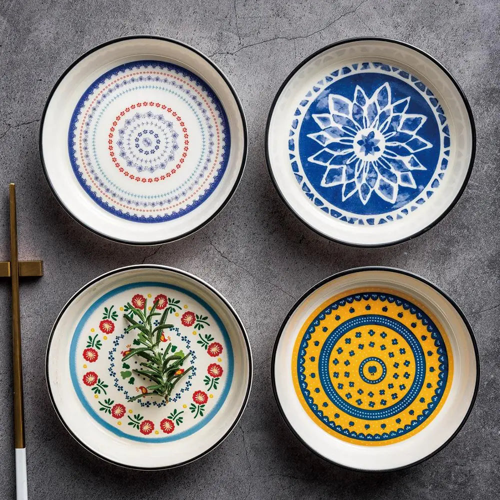 Set of four ceramic floral bone china round serving plates featuring unique hand-painted patterns in vibrant blue red yellow and green with black rims.