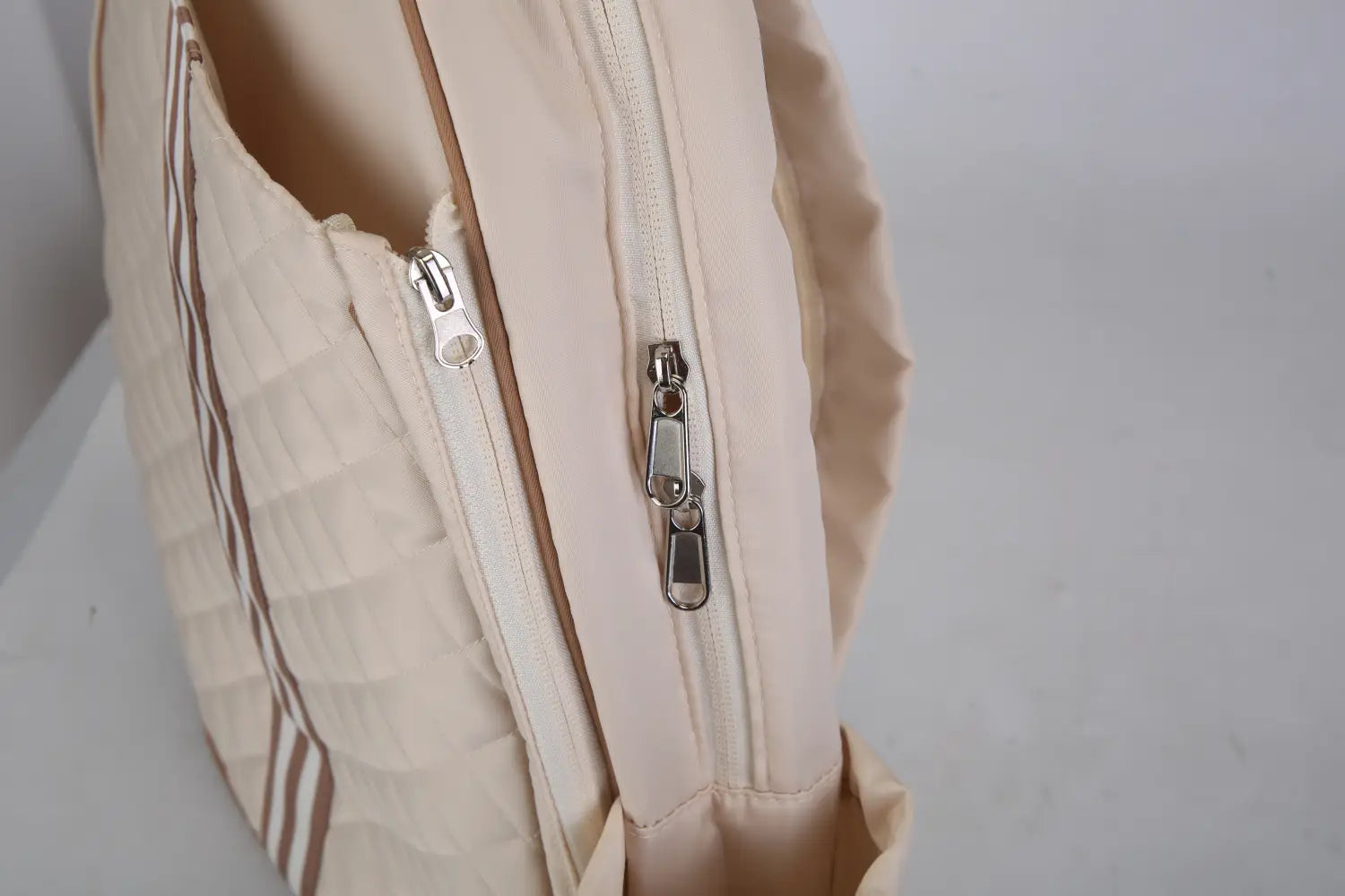 sac bandoulière pour pickleball matelassé beige, imperméable, avec rayures verticales brunes et fermetures éclair argentées, doté d’une poche humide pour un usage sportif