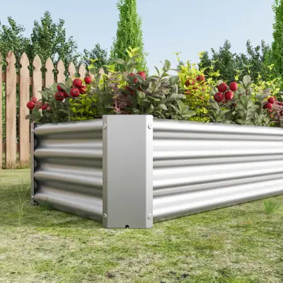 Lecho elevado de jardín de metal, maceta galvanizada plateada de 4x2x1 pies, fabricada en metal corrugado, con plantas verdes y rojas creciendo en su interior.