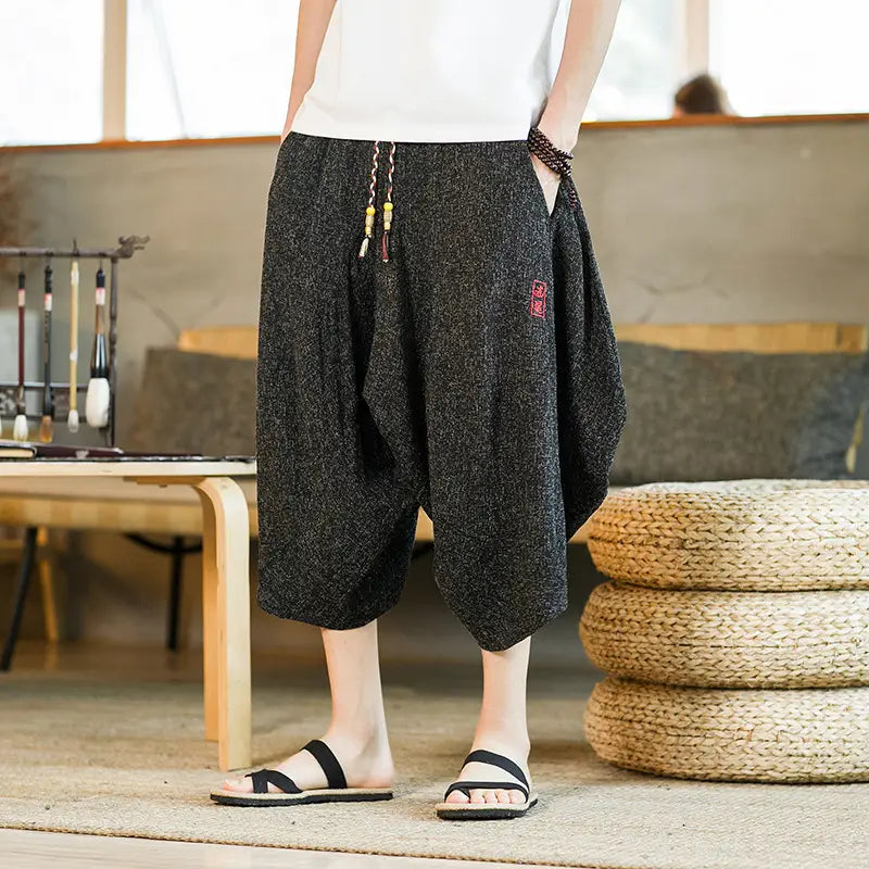 Herren-Shorts aus bedrucktem Baumwollstoff im Lantern-Harem-Look mit weitem Bein in Schwarz, mit Kordelzug-Taille und dezenter roter bestickter Patches-Applikation.