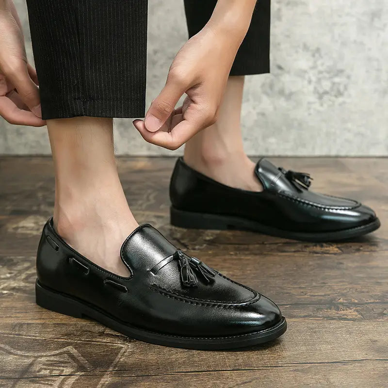 black leather tassel loafers with a polished finish and classic design slip on shoes shown from the back side