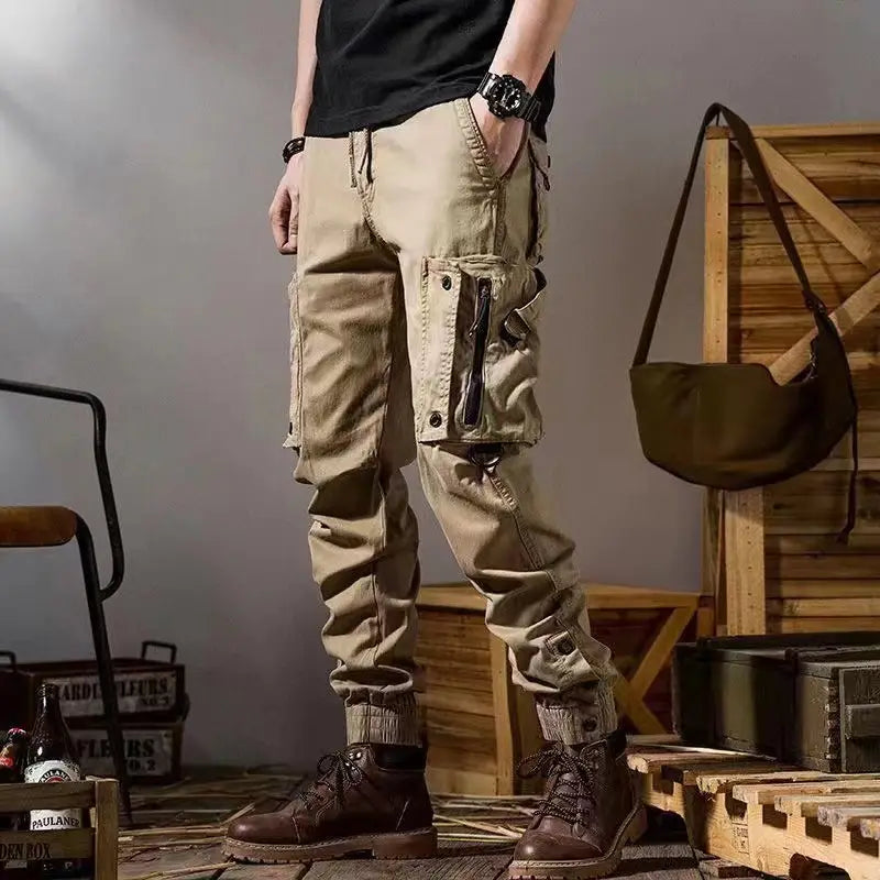 Beige men tactical cargo pants with multiple pockets and a tapered fit designed for outdoor casual utility use.
