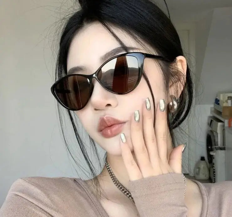 Lunettes de soleil rétro œil-de-chat UV380 avec des verres brun foncé et un cadre noir léger et élégant, pour la mode et la protection UV.