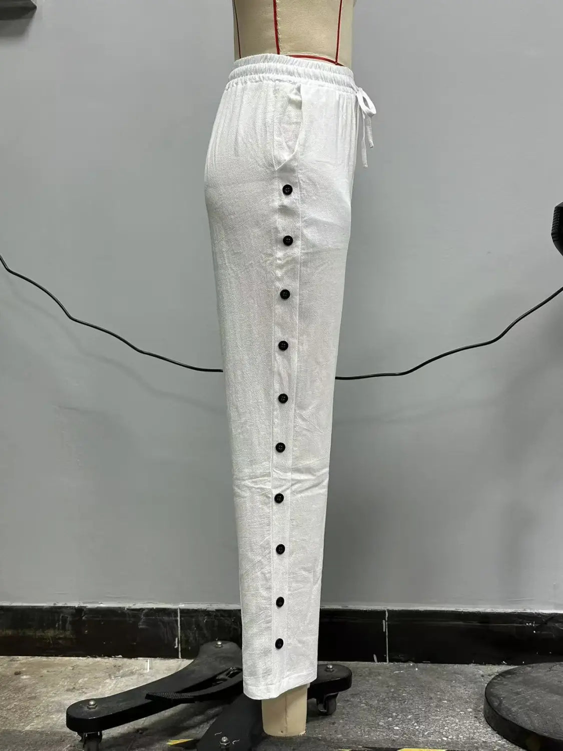 White cotton cropped patchwork casual pants for women featuring black buttons down the front and a drawstring waist.