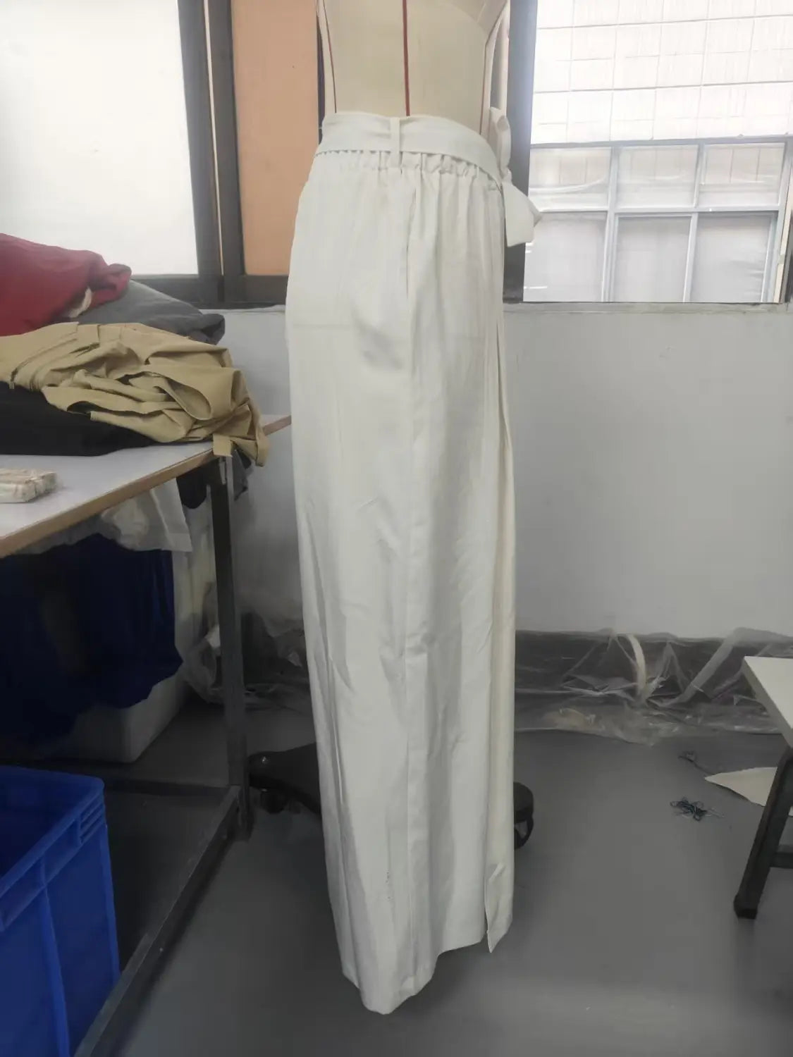 Un pantalon blanc ample à taille haute, avec une taille froncée et une fente latérale, conçu comme un pantalon ample et décontracté.